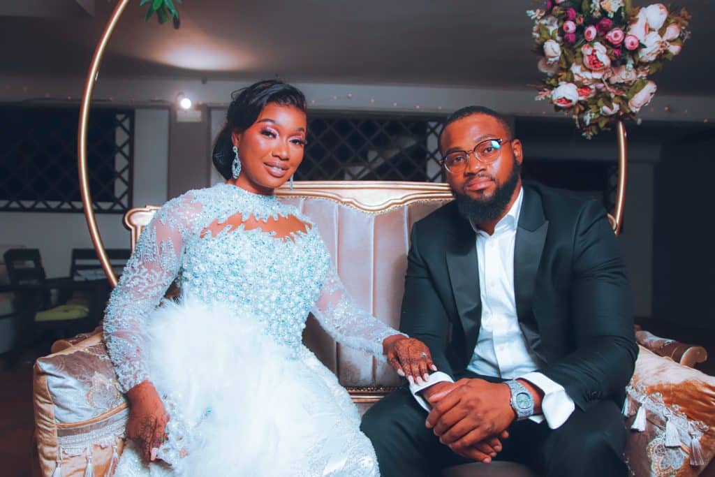 married couple pose for a photo in a long-sleeved wedding dress