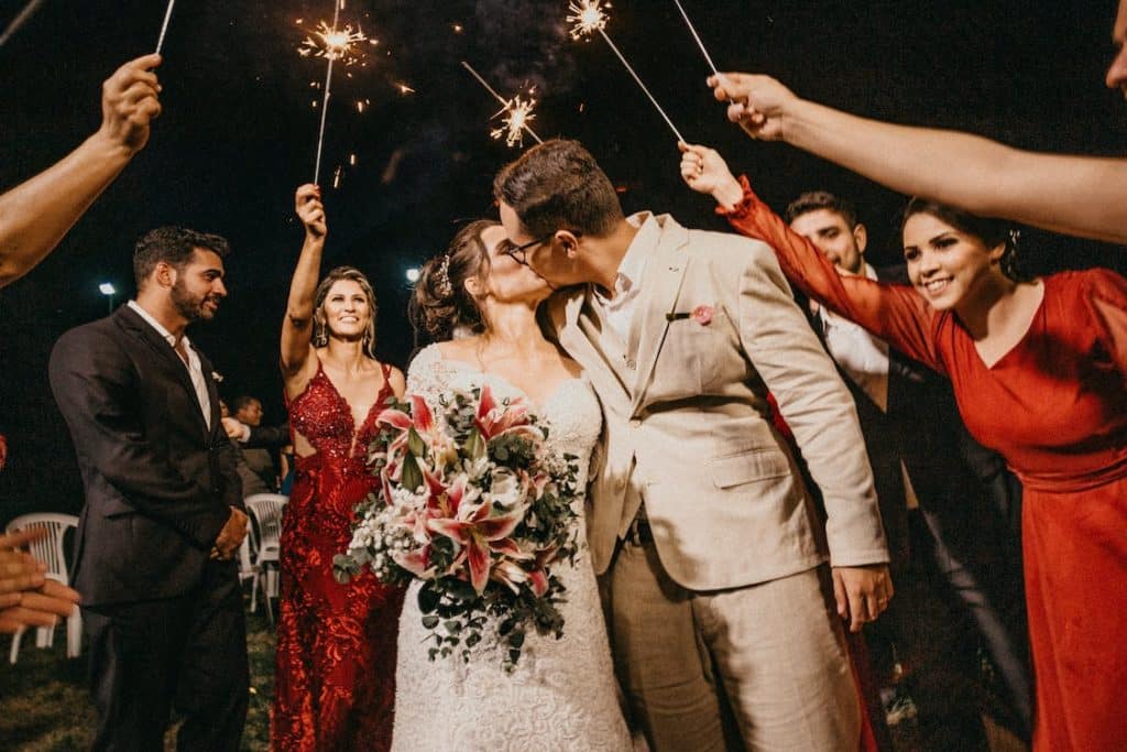 married couple kiss as as guests wave sparklers in the air at a winter wedding