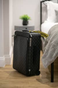 Louis Vuitton Suitcase next to a bed