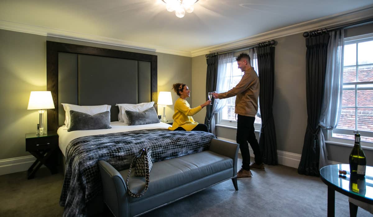 Two people in a hotel room at one warwick park doing a toast with champagne glasses