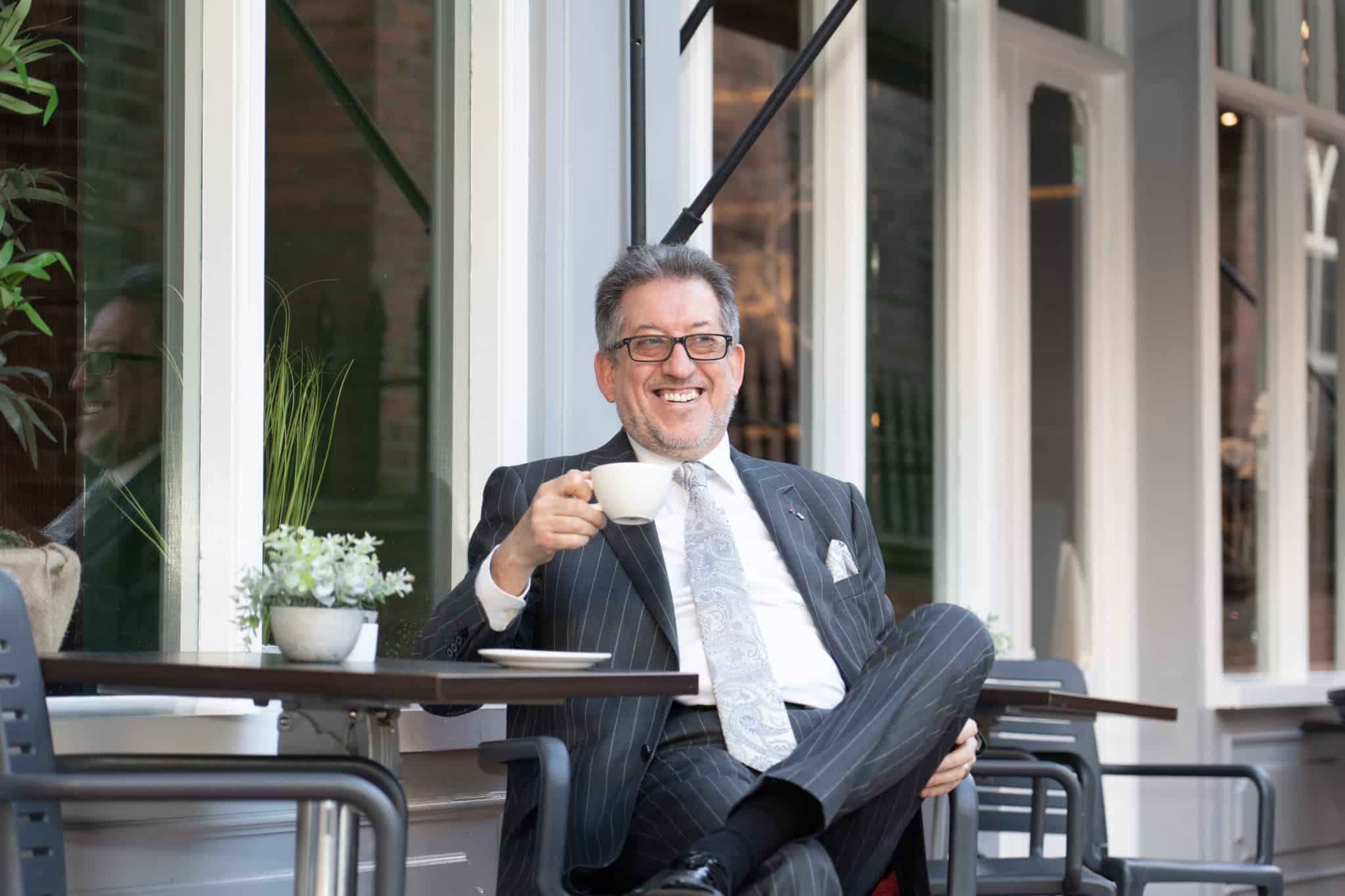 Luis Alves holding a cup while sitting down at a table