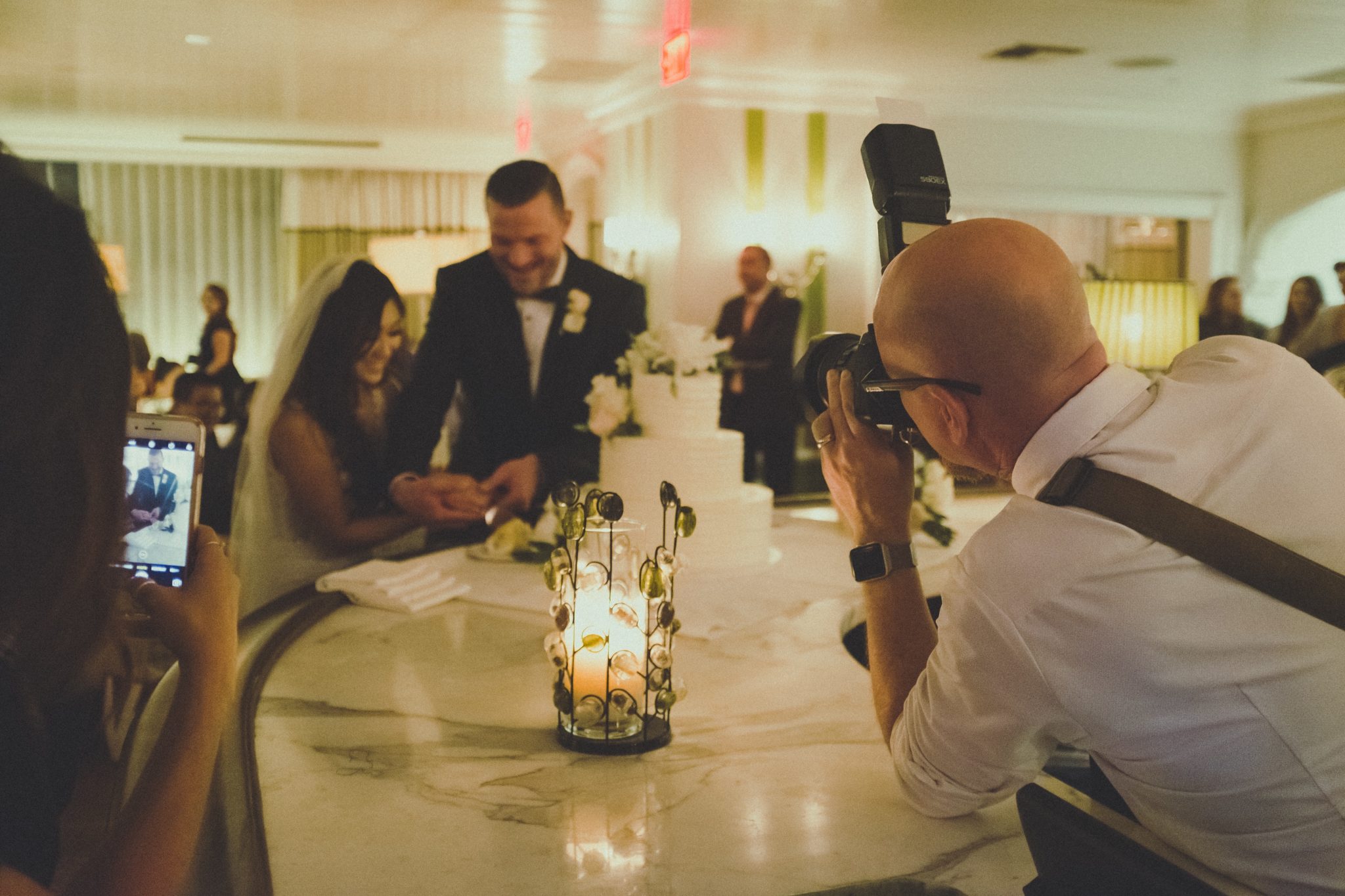 Photographer taking an image of wedded couple cutting their wedding cake