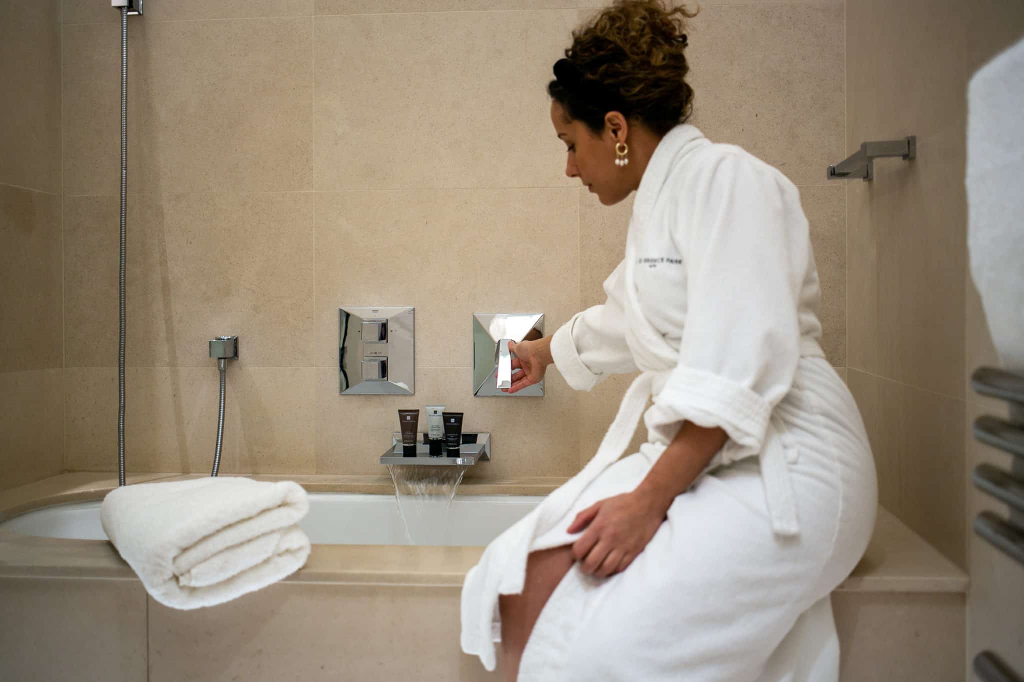 Woman wearing a bathrobe preparing a bath at one Warwick Park hotel