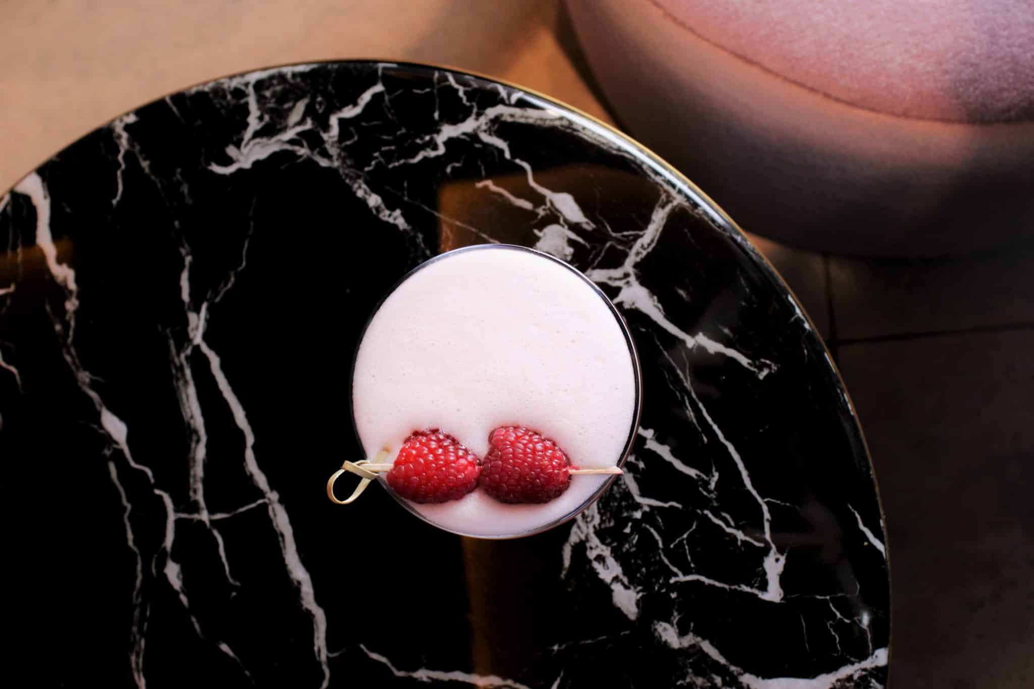 Cocktail with foam and two raspberries