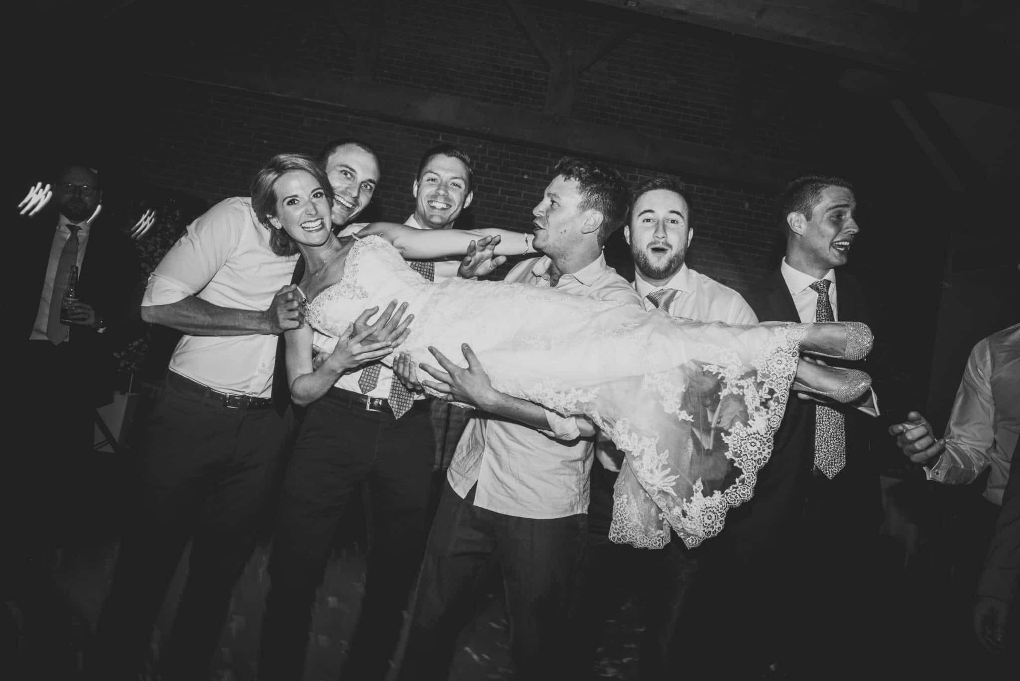bride being picked up by groomsmen for a photo