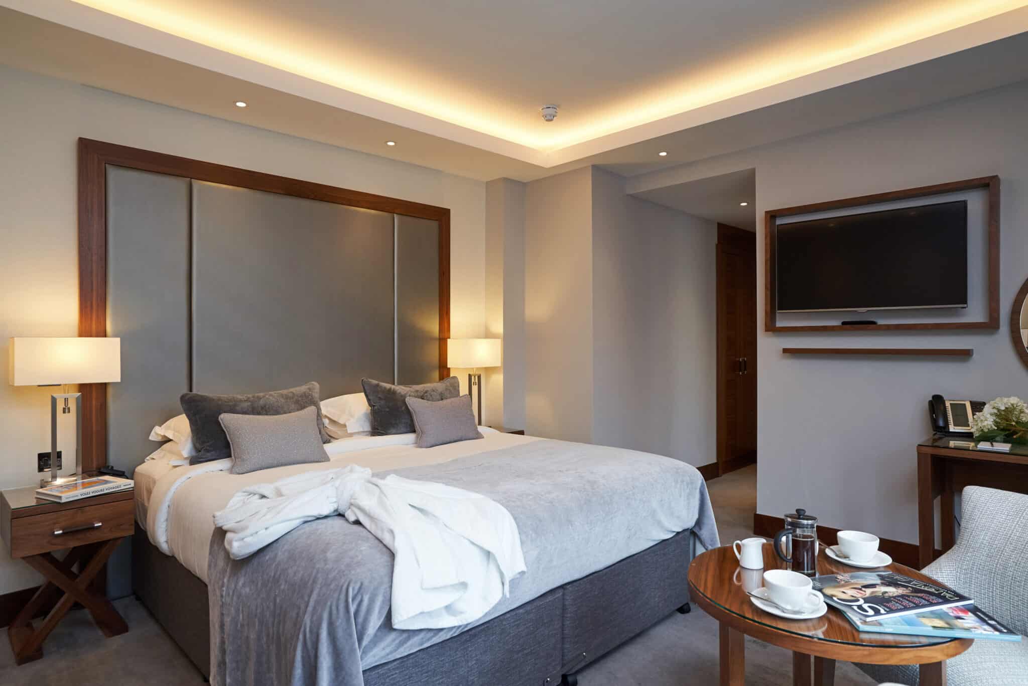 Spacious luxury hotel room featuring a double-size bed, stylish grey interior, and mood lighting.