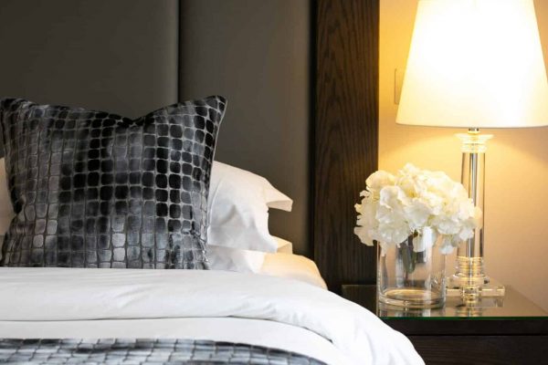 Luxury Tunbridge Wells hotel bed featuring bedside table with glowing lamp shade