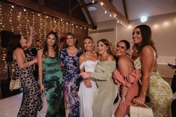 Bride and friends celebrating at a stylish hen party venue in Kent with string lights, wooden beams, and a lively atmosphere.